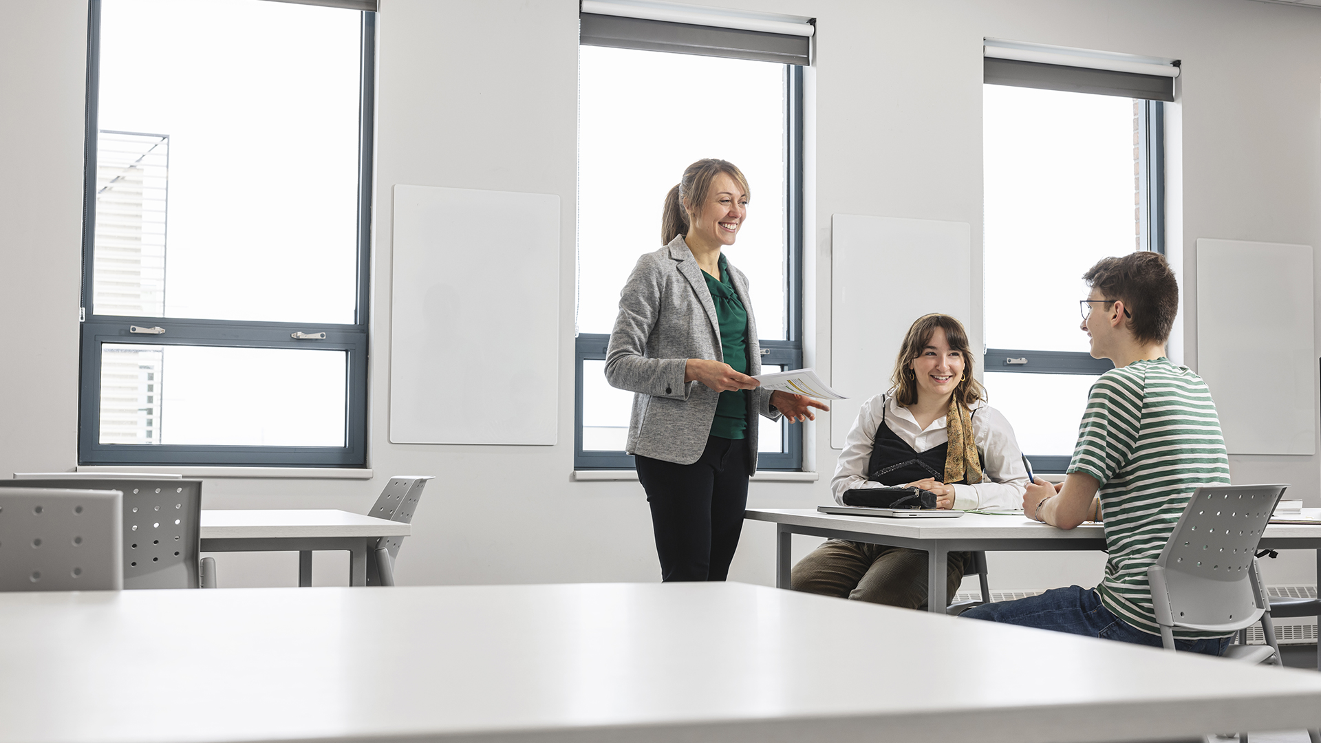 Professeur parlant à deux étudiants en classe